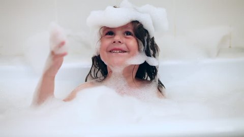 Adorable bath baby girl with soap suds on hair