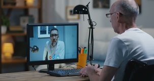 Medium shot of a disabled man in wheelchair talking to his doctor during a video chat