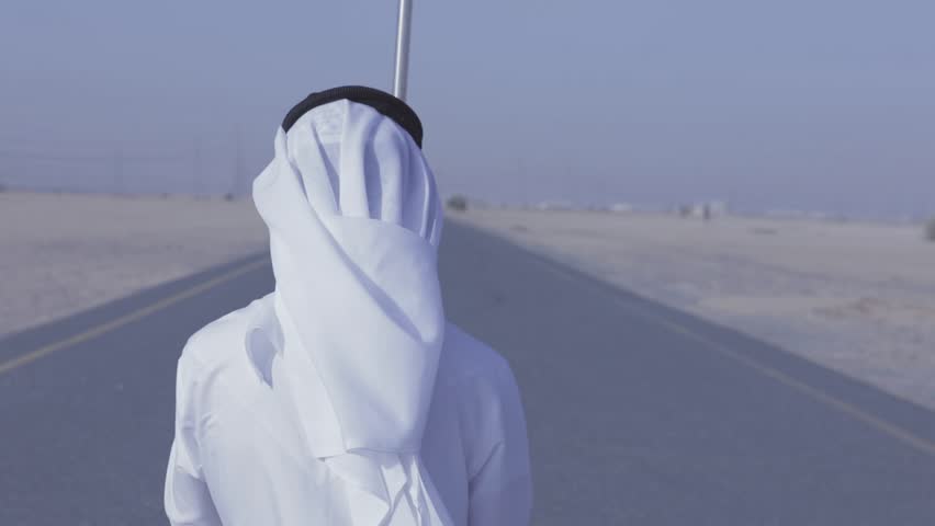 Arab man holding UAE flag in the desert 