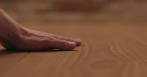 Slow motion closeup man hand touches ash wood floor