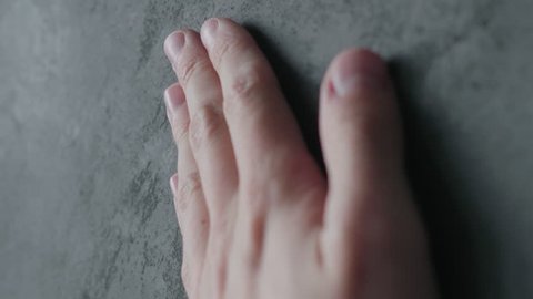 Slow motion man hand touches decorative concrete finish
