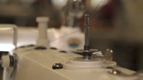 In slow motion video in a garment factory, a sewing machine embroiders various companies and engravings. Concept of: Automated work, Sewing machine, Engraving, Thread, Fabric, Needle.