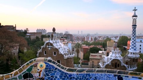 Barcelona city sunrise morning view from Guell Park with colorful mosaic buildings in tourist attraction Park Guell. Barcelona, Spain. With camera pan