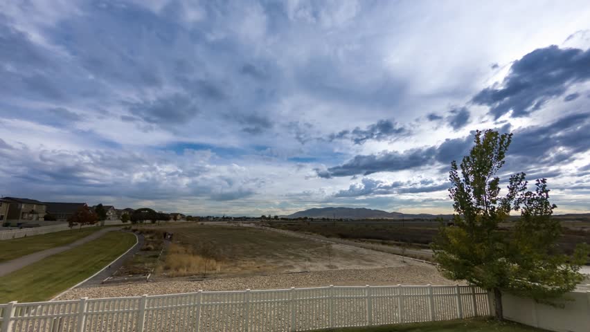 Cirrus clouds blow one direction while cumulus clouds blow another in this tranquil time lapse of a cloudscape over a meadow.