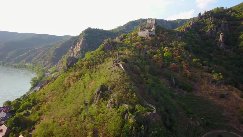 Aerial circling and fly over view of medieval Durnstein castle ruin and town in Wachau valley Lower Austria along the river Danube
