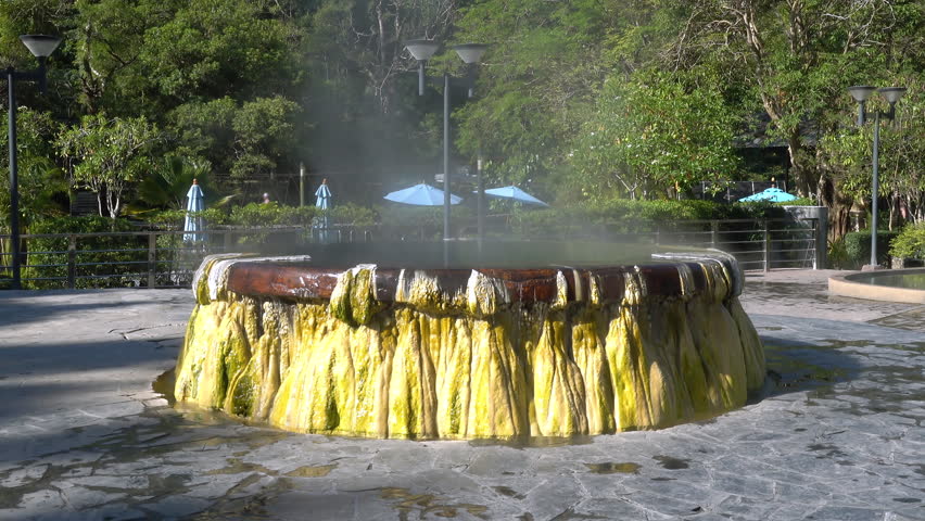 Steam rise from famous hot spring well in Raksa Warin public park, Ranong, Thailand. Tilt or pan down.