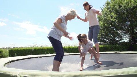 Slow motion sequence of granddaughter bouncing on trampoline with grandmother and mother. Shot on Sony FS700 at frame rate of 100fps