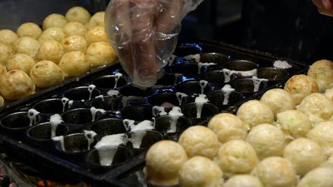 Slow Motion asian vendor prepare a delicious Takoyaki. Process to cooking the popular Ball-shaped Japanese snack made of wheat flour-based dumpling fried batter and cooked in a special moulded pan-Dan