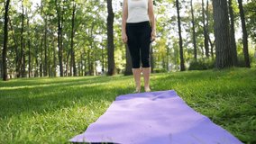 4k video of 40 years old woman doing fitness exercises on mat in local park. People taking care of their mental and physical health out in nature