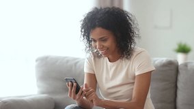 Happy young african american woman winner feel overjoyed celebrating bid win success victory looking at smartphone, excited black girl screaming yes winning online game app on cell phone at home