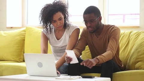 Worried young african american couple calculate bills pay online on laptop discuss financial problem high taxes expenses, black family stressed about paperwork talk about unpaid bank debt bankruptcy