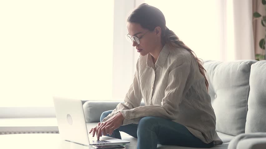 Serious young woman freelancer working on freelance from home typing email on laptop, focused girl using computer for study online at home sitting on couch, female user busy on distance internet job Royalty-Free Stock Footage #1028900237