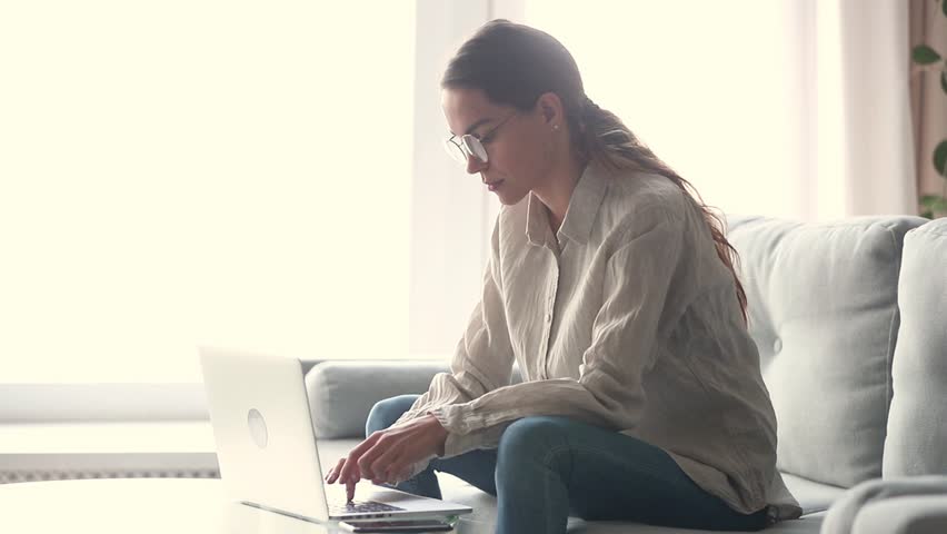 Serious young woman freelancer working on freelance from home typing email on laptop, focused girl using computer for study online at home sitting on couch, female user busy on distance internet job Royalty-Free Stock Footage #1028900237