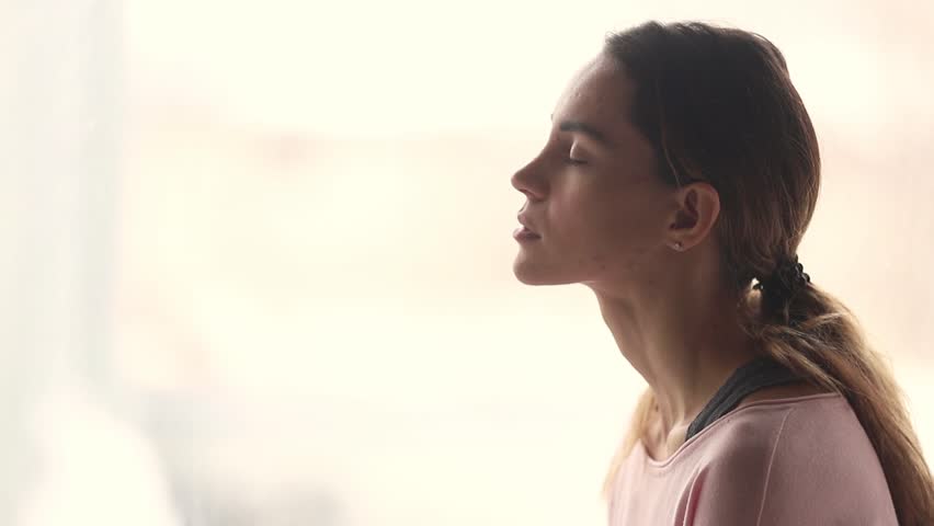 Calm young woman taking deep breath of fresh air relaxing meditating with eyes closed enjoying peace, serene tranquil girl doing yoga pranayama exercise feel no stress free relief, profile side view | Shutterstock HD Video #1028900276