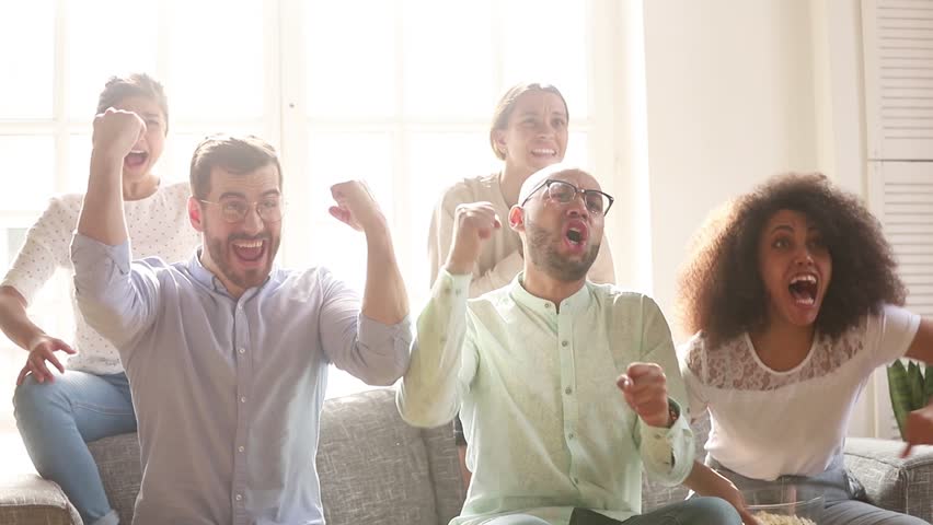 Overjoyed multicultural friends group football fans watching sport tv game sit on couch together, diverse happy people excited by goal score scream celebrate victory support cheering winning team Royalty-Free Stock Footage #1028900300