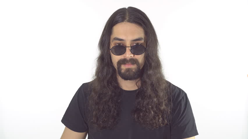 Portrait of a brunette funny man with a long curly hair, beard and mustache in sunglasses on a white background. Man search something
