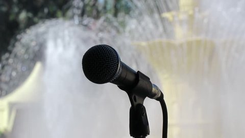 Black microphone on the stand in the Park on the background of the fountain.