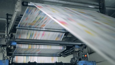 A machine works, rolling printed newspaper in typography facility.