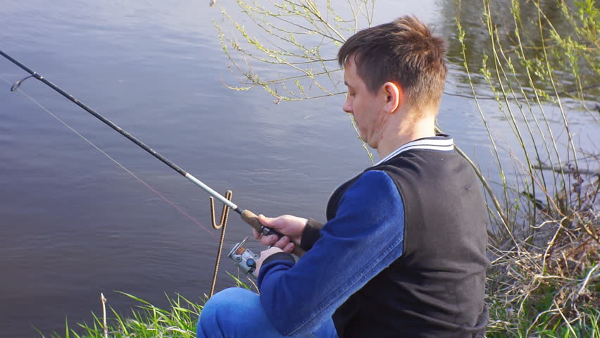 Fisherman pulls fish from shore.