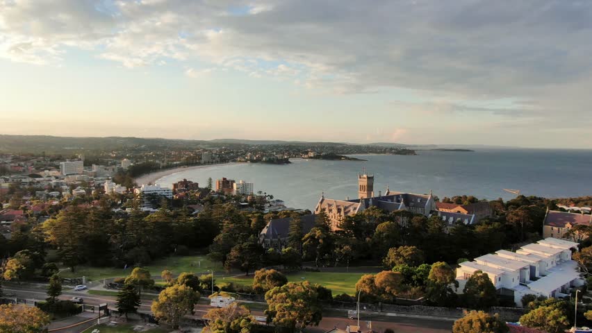 Beautiful aerial 4k drone evening footage of Manly, a beach-side suburb of northern Sydney, in the state of New South Wales, Australia with the historic management college in the foreground. Royalty-Free Stock Footage #1028910311