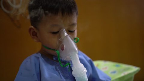 Sick Asian boy about 2 years and 8 months in hospital using inhaler containing medicine to stop coughing from disease like flu or RSV, Respiratory Syntactical Virus