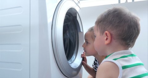 Cute Children Looks Inside the Washing Machine. Cylinder Spinning Machine. Concept Laundry Washing Machine, Industry Laundry Service.