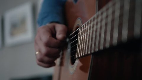 Musician playing acoustic guitar fingers hand close.