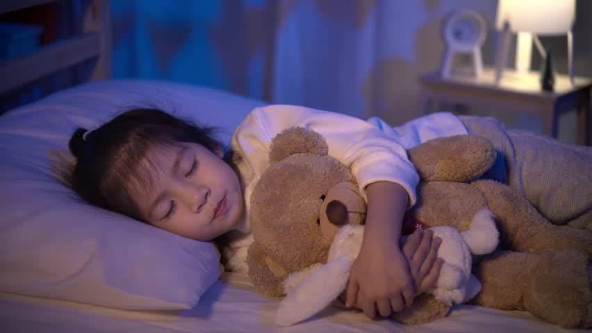 Mother putting blanket on and stroking head for her little girl daughter on bed in a dark bedroom at night, Child asian girl hug teddy bear, Comfortable children at home concept | Shutterstock HD Video #1028938088