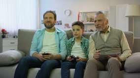 Granddad and dad cheering for boy playing video game, hobby and leisure activity