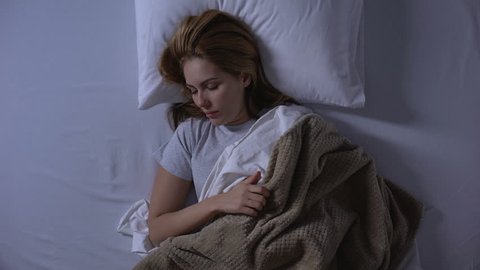 Blonde woman waking-up in morning feeling nausea, morning sickness, top-view
