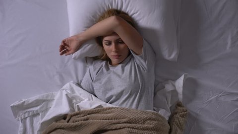 Sad lady lying in bed suffering from intestinal flu feeling nausea and dizziness