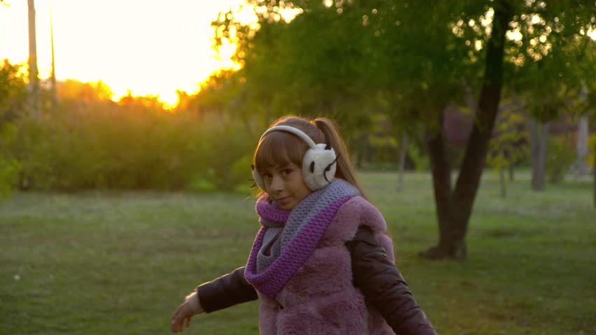 girl listening to music on headphones in the autumn park at sunset