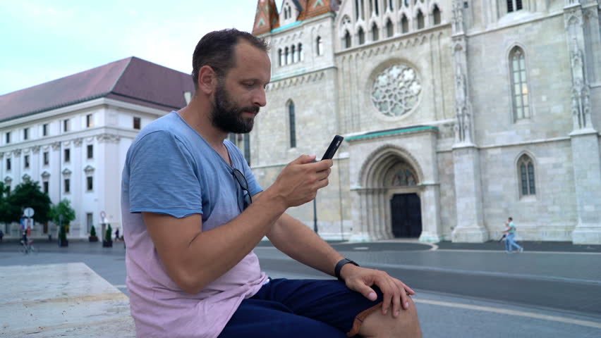 Young man texting on smartphone in old Budapest town