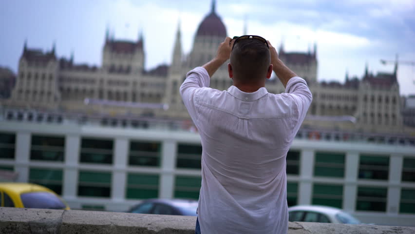Young man taking photo of Budapest parliament