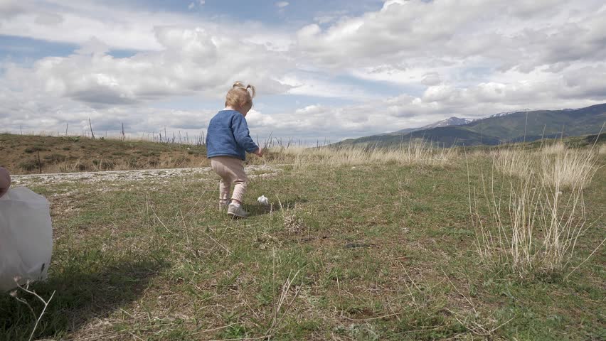 Little blond girl collecting garbage in nature , society against pollution