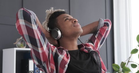 Young man listening music through headphones in office