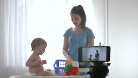 videoblog streaming live, cute baby boy with mom played by educational toys and filming new episode for vlog in streaming live on smartphone for subscribers in social networks in bright room