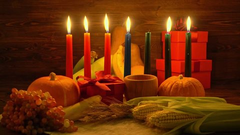Kwanzaa holiday concept with ignite seven candles red, black and green, corns, grapes, bananas, gift boxes, pumpkin, bowl and fruits