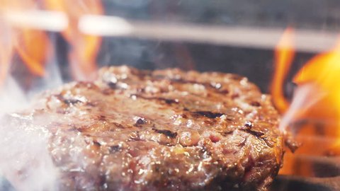 Tasty meat for a burger cooked on a fiery barbecue grill. Close up of chief cooked oil unhealthy, but very satisfying protein tasty burger in casual bar