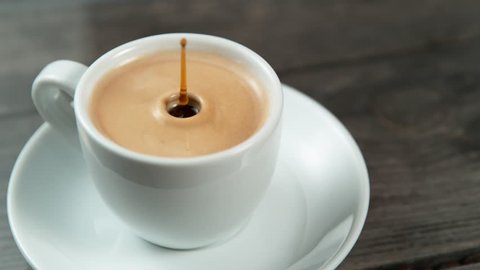 Drop falling into a cup of coffee in super slowmotion. Stockvideo