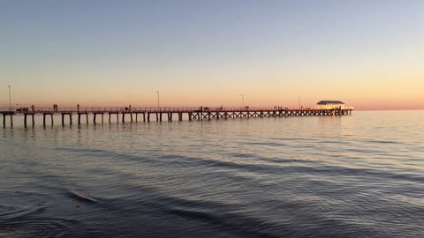 ADELAIDE - MAY 06 2019:Silhouette of Henley Beach pier at dusk. Henley Beach pier is a very popular tourist attraction and sightseeing in Adelaide the capital city of South Australia.
