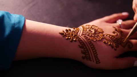 woman applying henna design on other woman's hand during Indian wedding ceremony
