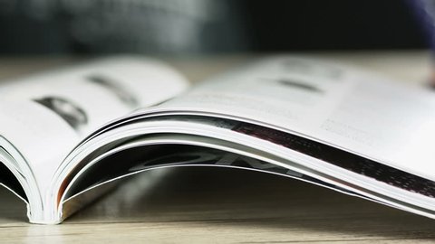 Close up shot of someone flipping the pages of a magazine