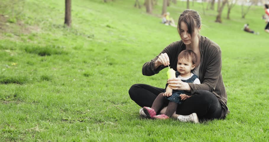 Mother blowing bubbles with baby girl. Cinematic 4K footage.