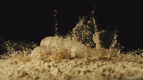 SLOW MOTION: Ginger root falls in powder and powder scatters around