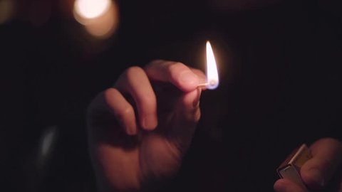 Burning match in male hands on a dark background close-up.