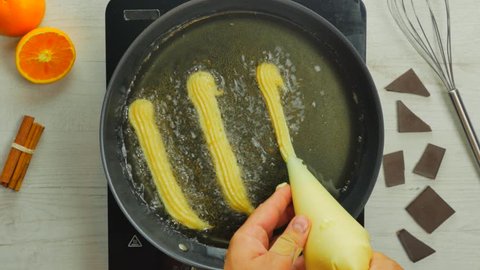 Churros pastry frying on a pan / Chef squeezing out sweet pastry into oil