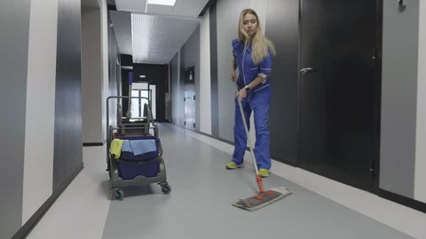 Caucasian janitor woman mopping floor in hallway office building using mop and cleaning equipment cart