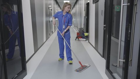 Young Female Janitor Cleaning Floor With Mop In Office corridor. Office cleaning company employee working