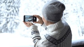Young woman uses a smartphone to video a beautiful view in the mountains, rear view
